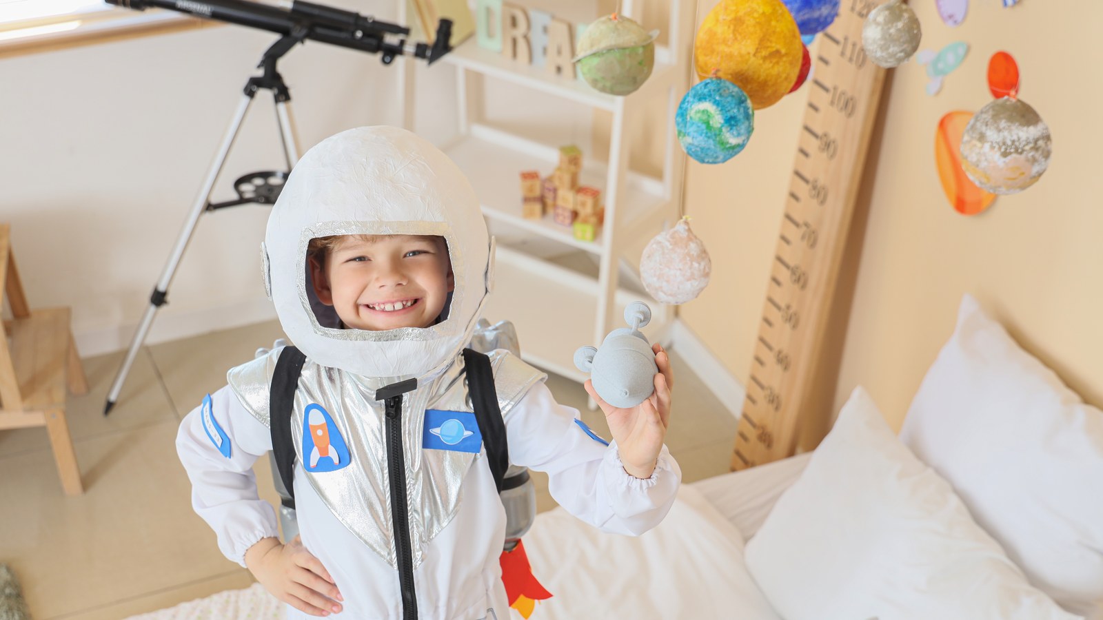Smiling boy in an astronaut costume with handmade planets