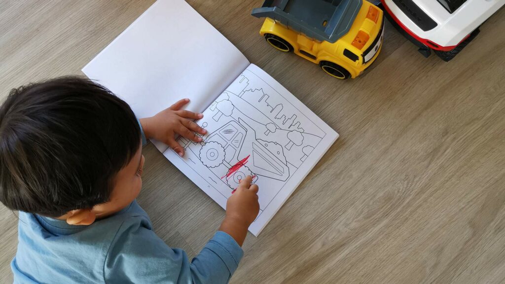 Toddler coloring in the Construction Site Coloring Book by Happy Little Llama